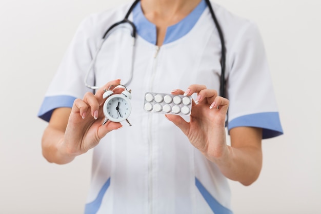 Doctor hands holding pills and a clock