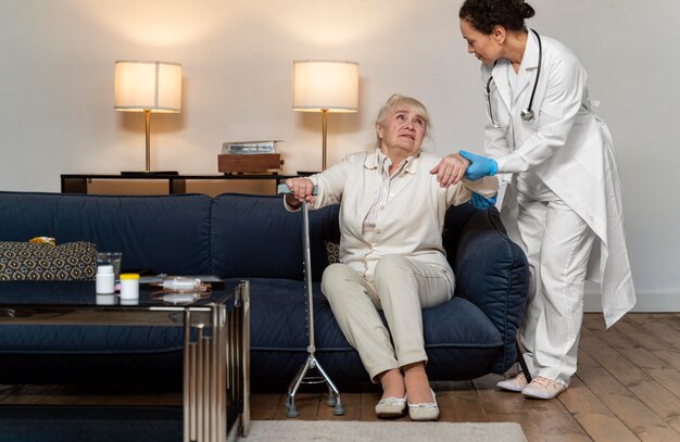Doctor helping her old patient to stand up