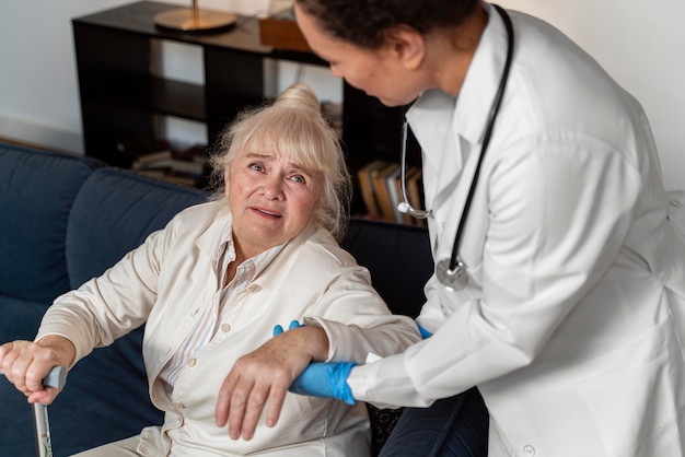 Doctor helping her old patient to stand up