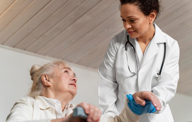 Doctor helping her old patient to stand up