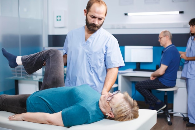 Doctor helping old woman with knee pain