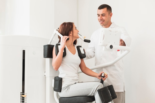 Free photo doctor helping patient with medical work out machine