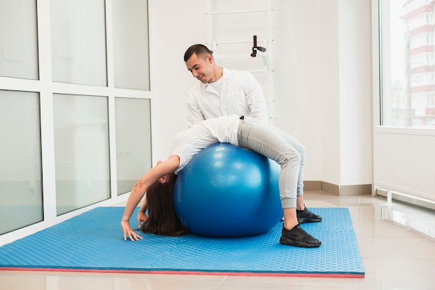 Doctor helping patient with therapeutic ball