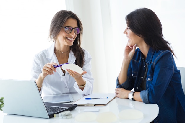 Doctor and her patient choosing mammary prosthesis in the office.