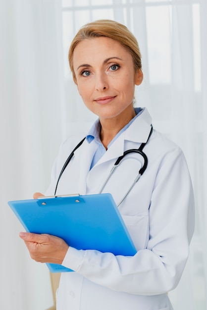 Doctor holding clipboard looking at camera