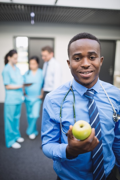 Free photo doctor holding green apple in hospital corridor