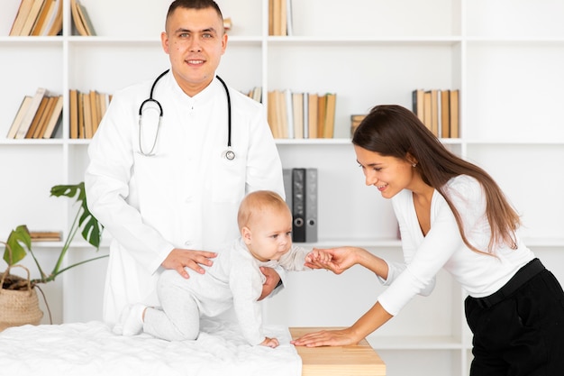 Doctor holding little baby and looking at photographer