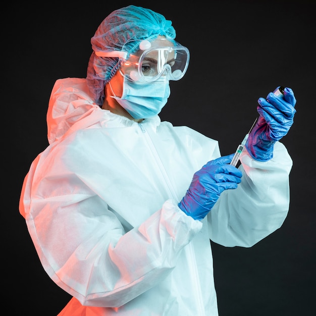 Doctor holding a syringe while wearing a medical mask