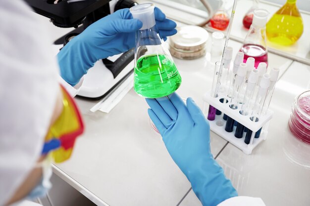 Доктор держит пробирку, колбу с жидкостью в специальной лаборатории, готовящейся к экспериментам