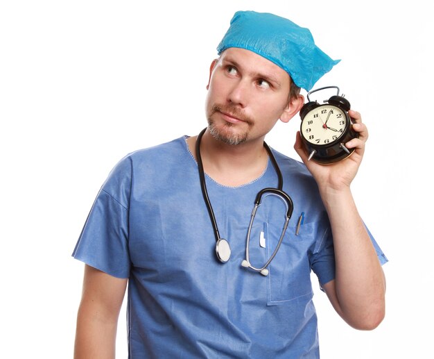 白い壁に隔離された時計を保持している医師