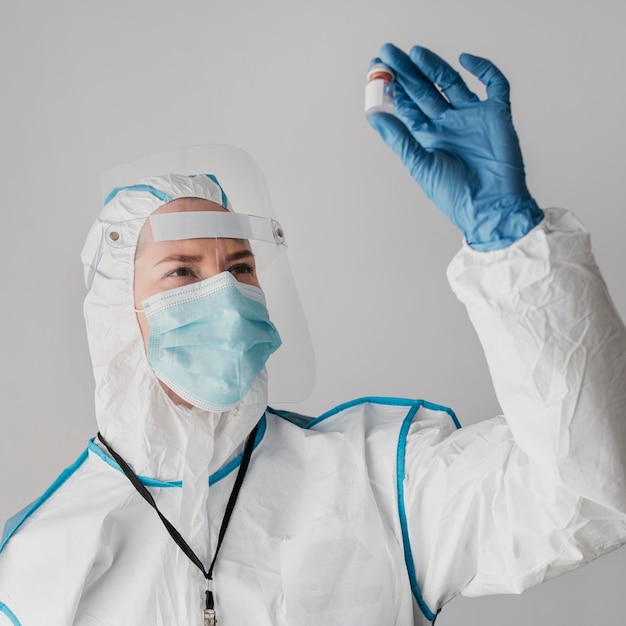 Doctor holding a vaccine bottle while wearing protective equipment