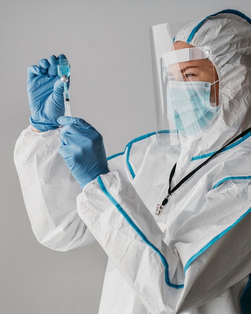 Doctor holding a vaccine bottle while wearing protective equipment