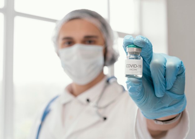 Доктор держит бутылку вакцины
