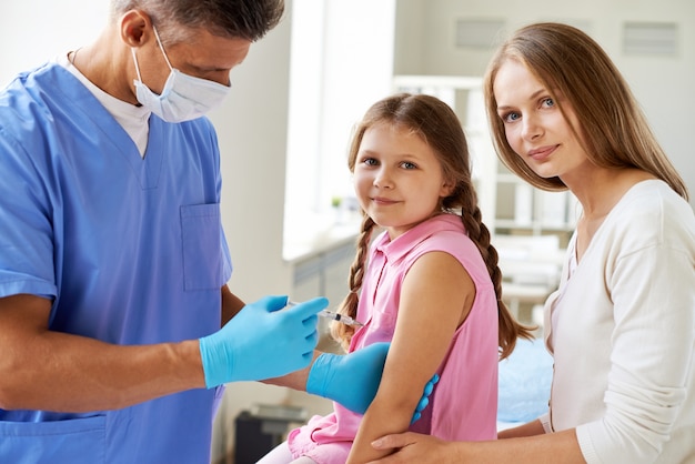 Doctor injecting vaccine to little girl