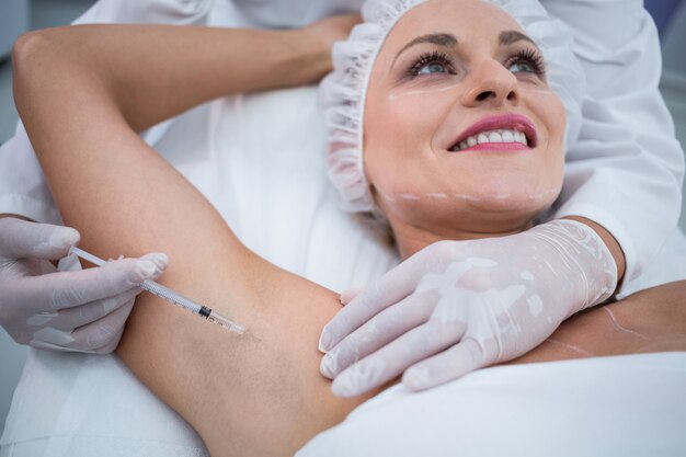 Doctor injecting woman on her arm pits