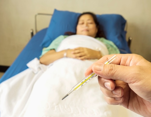 Free photo a doctor is looking at thermometer for measuring body temperature of his patient.