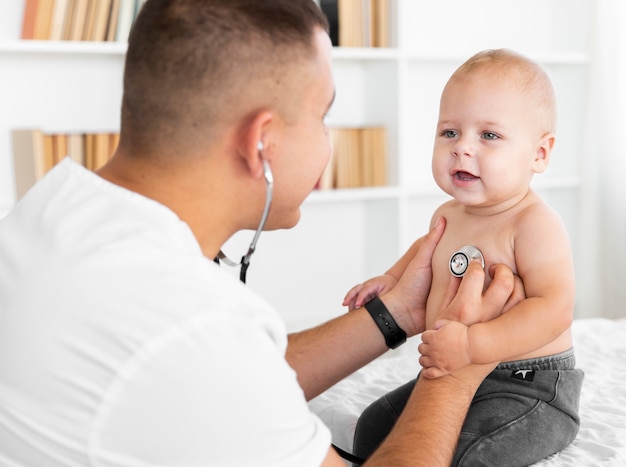 Доктор слушает маленького ребенка со стетоскопом