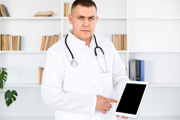 Free photo doctor looking at photographer and holding photo mock up