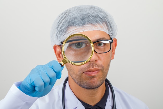 Doctor looking through magnifying glass in white coat and hat