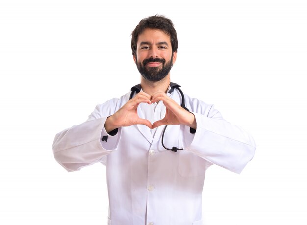 Doctor making a heart with her hands over white background