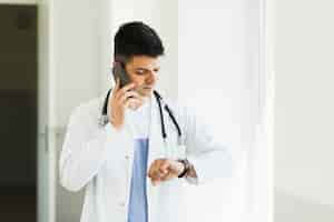 Free photo doctor making phone call and checking time