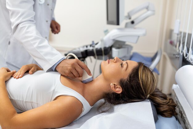 Doctor making ultrasound of thyroid gland to woman patient in clinic Diagnosis and treatment of autoimmune thyroiditis concept