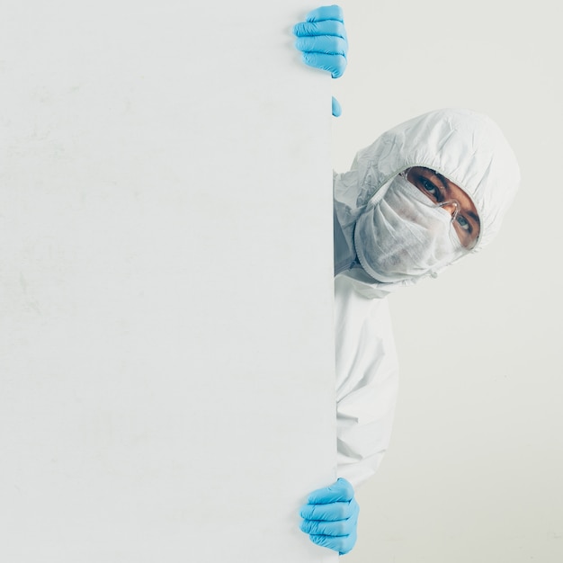 Free photo a doctor in mask, gloves and protective suit hiding and looking