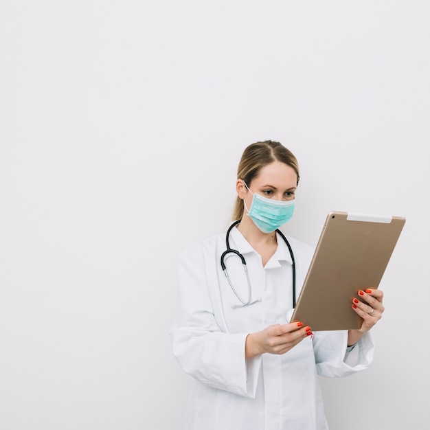 Doctor in mask looking at tablet