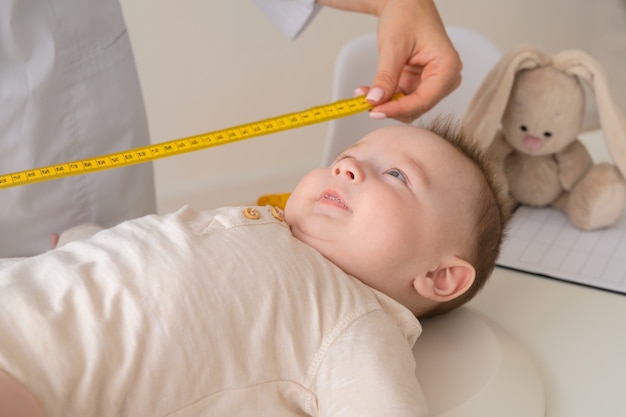 Free photo doctor measuring baby high angle