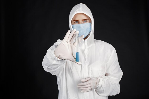 医療用マスクの医者。コロナウイルスのテーマ。黒い壁に隔離されています。防護服を着た女性。