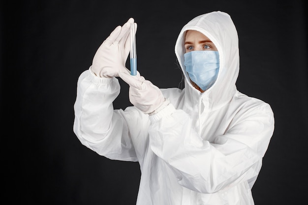 医療用マスクの医者。コロナウイルスのテーマ。黒い壁に隔離されています。防護服を着た女性。