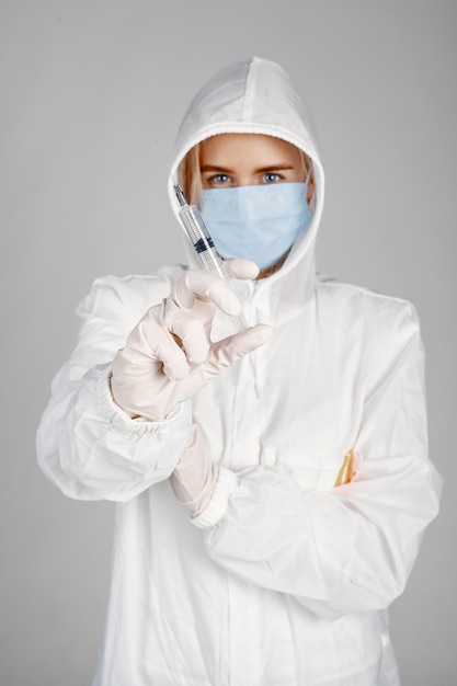 Doctor in a medical mask. Coronavirus theme. Isolated over white wall. Woman in a protective suit.