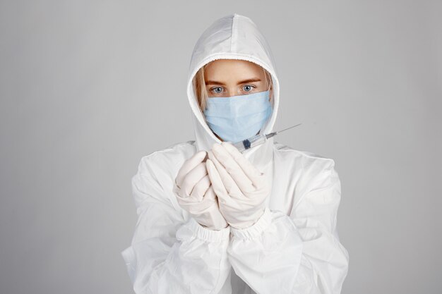 医療用マスクの医者。コロナウイルスのテーマ。白い壁に隔離。防護服を着た女性。