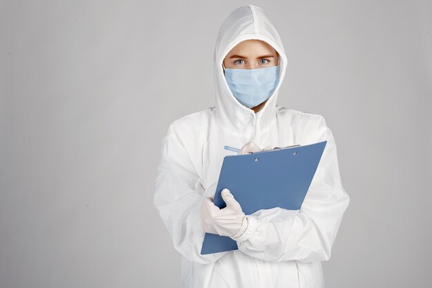 의료 마스크에 의사. 코로나 바이러스 테마. 흰 벽 위에 절연. 보호 복에 여자입니다.