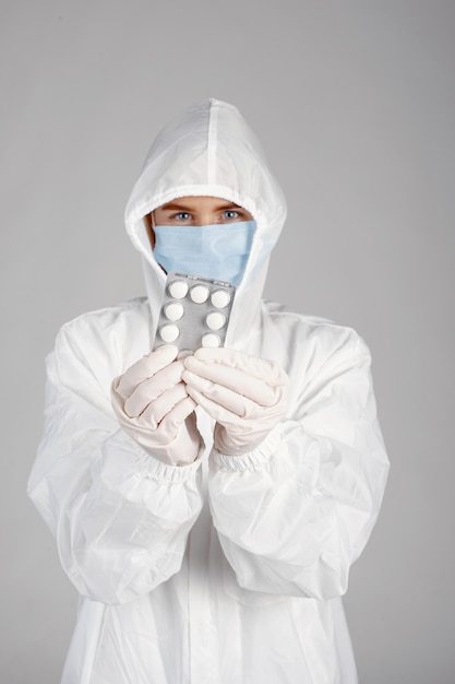 Doctor in a medical mask. Coronavirus theme. Isolated over white wall. Woman with pills.