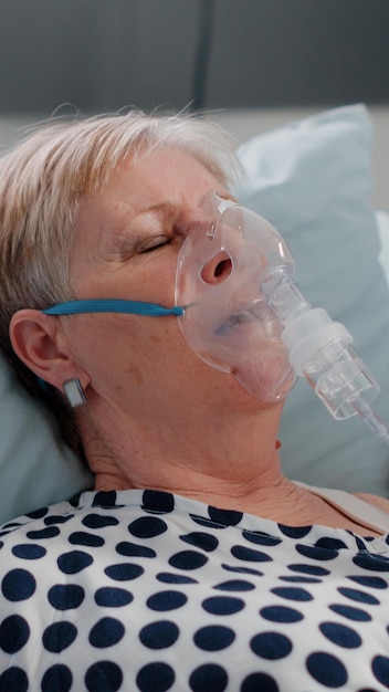 Free photo doctor and nurse giving assistance to heavy breathing woman, using oxygen tube to cure respiratory issues in bed. medical team helping aged patient with hyperventilating illness.