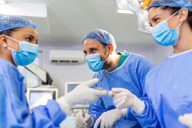 Doctor and nurse medical team are performing surgical operation at emergency room in hospital assistant hands out scissor and instruments to surgeons during operation