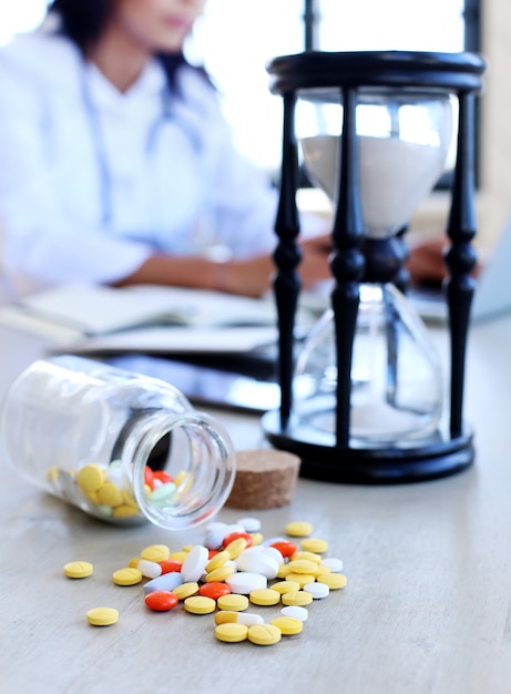 Free photo doctor at the office with pills and hourglass