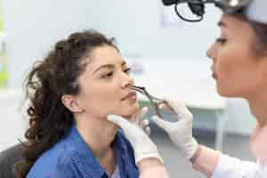 Free photo doctor otorhinolaryngologist checking nose with otoscope of patient at hospital nasal congestion sinusitis allergy concept