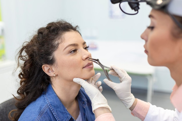 Doctor otorhinolaryngologist checking nose with otoscope of patient at hospital Nasal congestion sinusitis allergy concept