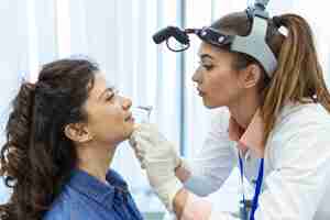 Free photo doctor otorhinolaryngologist checking nose with otoscope of patient at hospital nasal congestion sinusitis allergy concept