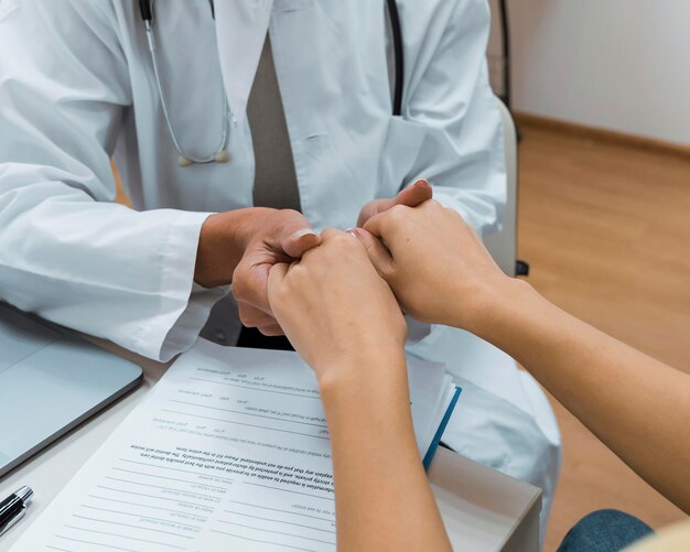 Doctor and patient holding hands after bad news close-up