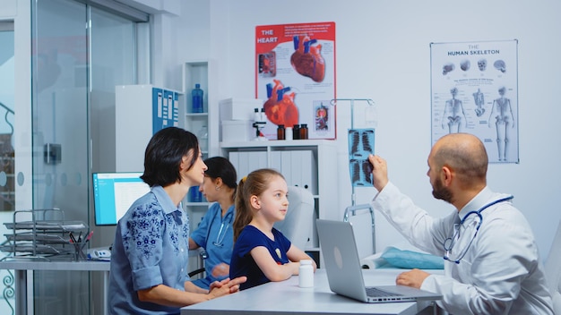 의사와 환자들이 진료실에 앉아 엑스레이를 보고 있습니다. 의료 서비스 상담, 클리닉 병원 캐비닛에서 방사선 치료를 제공하는 의학 전문 의사