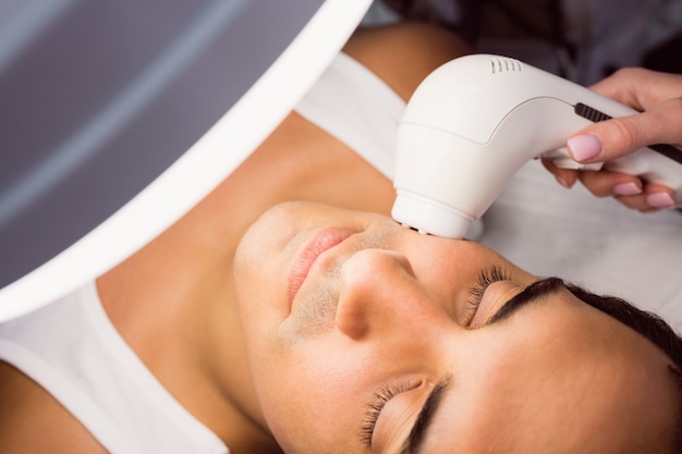 Doctor performing laser hair removal on patient face