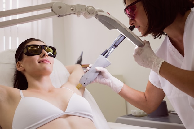 Doctor performing laser hair removal on patient skin