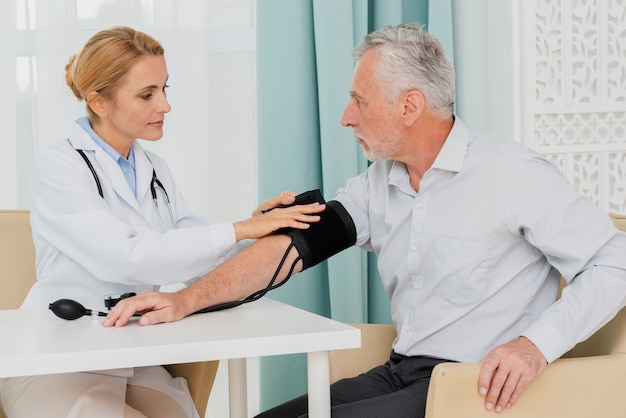 Free photo doctor placing blood pressure cuff