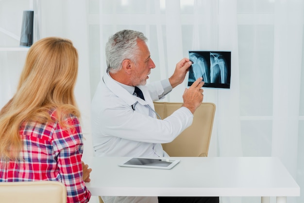 Free photo doctor pointing at x-ray with patient