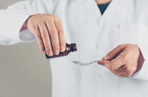 A doctor pouring syrup for someone. side view.