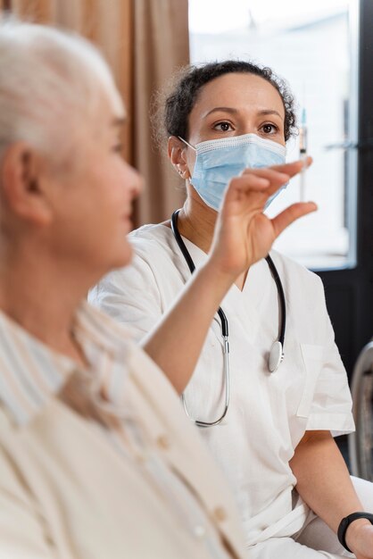 Doctor preparing the vaccine for a senior woman