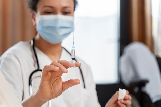 Doctor preparing the vaccine for a senior woman